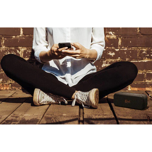 Klipsch Nashville 18W Portable Bluetooth Speaker Waterproof 360 Audio
Person sitting cross-legged on a wooden floor using a smartphone with a brick wall background