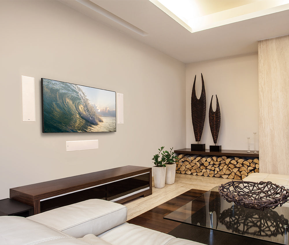 KEF Ci4100QL-THX In-Wall LCR Architectural Single Speaker
Modern living room with a TV displaying a natural scene, decorative vases, and a firewood stack.