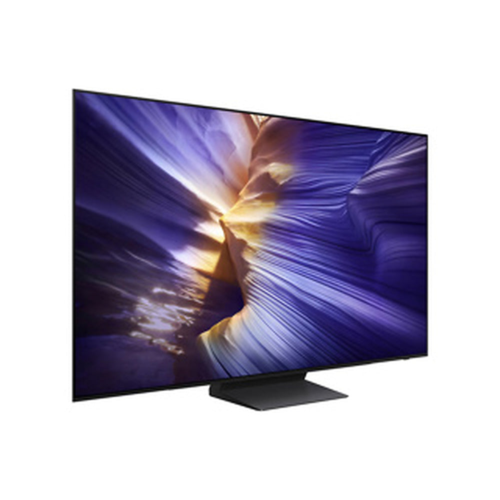 A modern flat-screen TV on a slim stand, shown at a three-quarter angle against a plain white background. The screen displays a colorful canyon scene with purple, blue, and gold tones.