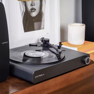 Victrola VPT-2000-BLK-ORT Onyx Turntable Ortofon Sonos Ready
Victrola turntable on a wooden surface with a candle and framed picture in the background