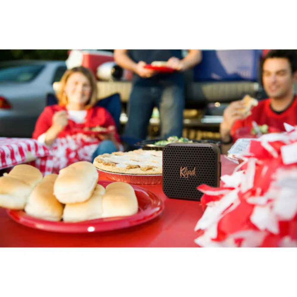 Klipsch Austin 18W Portable Bluetooth Speaker Waterproof Microphone
Picnic scene with food and Klipsch speaker, people in the background
